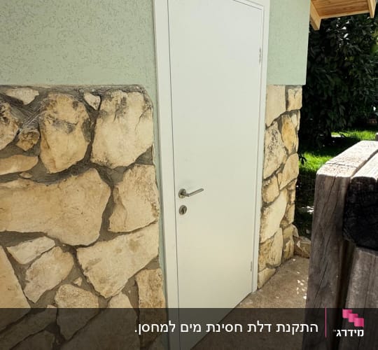 דלת לבנה עם ידית על קיר אבן